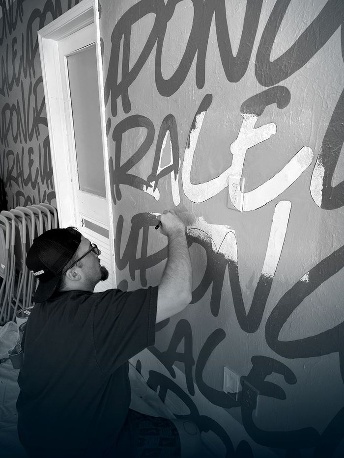 Brent Naquin painting a lettering mural